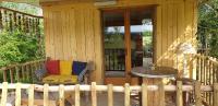 a porch of a wooden cabin with a chair and a table at LA CABANE PERCHEE in Villelaure