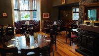 een restaurant met tafels en stoelen en een open haard bij Corriegarth Hotel in Inverness