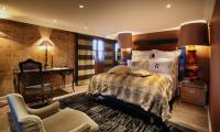 a bedroom with a bed and a desk and a chair at Hotel Le Saint Roch in Courchevel
