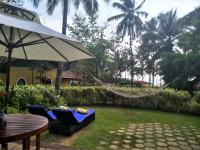 a patio with two chairs and a table and an umbrella at Taj Holiday Village Resort & Spa, Goa in Candolim