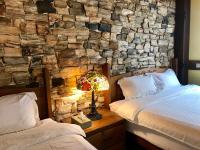 a bedroom with two beds and a stone wall at Rothenburg Lodge in Wujie
