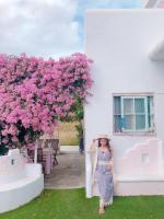 a woman standing next to a white building with pink flowers at Minami Kaze in Magong