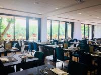 Un comedor con mesas y sillas y ventanas. en La Chartreuse Logis Hotel Restaurant, en Cahors