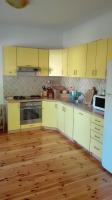 a kitchen with yellow cabinets and a wooden floor at Villa Nadija in Čanj