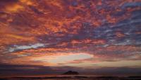 a cloudy sky over the ocean with a mountain in the distance at Ocean Sky Homestay in Toucheng