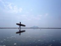 a person walking on the beach with a surfboard at Ocean Sky Homestay in Toucheng