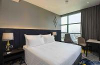 a hotel room with a bed and a desk and a window at Chatrium Hotel Riverside Bangkok in Bangkok