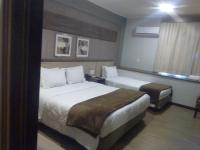 a hotel room with two beds and a window at Klein Ville São Leopoldo in São Leopoldo