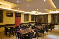 a dining room with wooden tables and chairs at Hotel Ganeshratna Executive Kolhapur in Kolhapur