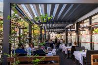 Un restaurante con mesas y gente sentada en las mesas. en Hotel Hvala Superior - Topli Val, en Kobarid