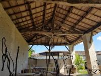 a patio with a wooden roof with chairs and tables at Les Hauts De Chalonne in Le Gond-Pontouvre