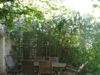 a table and chairs under a fence with white flowers at Le Mas De La Chérine in Quinson