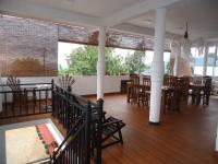 a dining room with wooden tables and chairs and windows at Nilowin Glenanore Guesthouse in Haputale