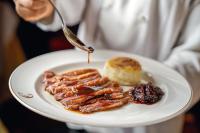 uma pessoa segurando um prato de comida com carne e um pastel em Country Club Lima Hotel – The Leading Hotels of the World em Lima