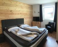 two beds in a room with a wooden wall at Almwirt in Bramberg am Wildkogel