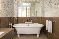 a bathroom with a white tub and a mirror at La Maison d&#39;Uzès Relais &amp; Châteaux in Uzès