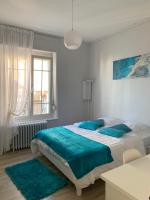 a white bedroom with a large bed with blue pillows at Relais Vacances à la Mer in Berck-sur-Mer