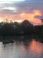 Song Ngư Riverside Homestay في كان ثو: شخصين في قارب على الماء عند غروب الشمس