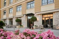 a building with tables and chairs and pink flowers at Artis Boutique Hotel in Szombathely