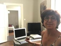 a woman standing in front of a desk with a laptop and a phone at Le gîte de l&#39;atelier in Bergerac