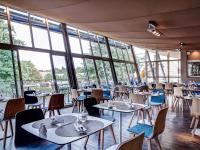 Un restaurante con mesas, sillas y ventanas. en Mercure Lyon Charbonnières, en Charbonnières-les-Bains