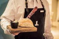 a chef holding a cutting board with a loaf of bread at Maran Suites & Towers in Paraná