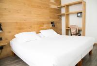 Dos camas en una habitación con paredes de madera. en Le Victor Hugo, en Montrouge