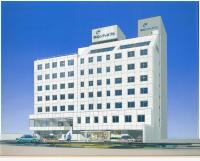 Un edificio blanco con coches aparcados delante. en Takamatsu City Hotel, en Takamatsu