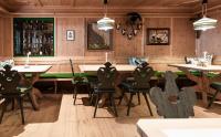 Un restaurante con paredes de madera y mesas y sillas. en Alpine Hideaway ZILLERTALERHOF - 4 Sterne Superior, en Mayrhofen