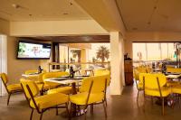 een restaurant met gele stoelen en tafels en een tv bij First Group Riviera Suites in Kaapstad