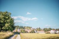 a dirt road through a field with houses in the background at Landhotel Aschenbrenner in Freudenberg