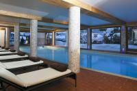 a pool in a hotel with lounge chairs and a swimming pool at Carlina in La Clusaz