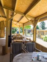 een restaurant met houten tafels en stoelen en een terras bij Camping De Grienduil in Nieuwland