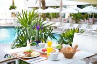 einen Tisch mit Frühstücksspeisen und Getränken neben einem Pool in der Unterkunft Lagoona by Isrotel Collection in Eilat