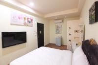 a bedroom with a white bed and a flat screen tv at Fasiter B&amp;B train station in Hualien City