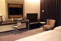 a bedroom with a desk and a television and a chair at Golden Tulip Glory Fine Hotel in Tainan