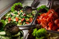 Un buffet de verduras con utensilios para servir. en CE Plaza Hotel, en Siófok