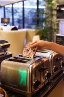 a person holding a piece of bread on a toaster at VIVE Hotel Waikiki in Honolulu