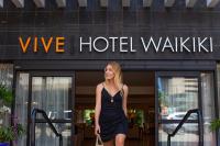 a woman walking in front of a hotel building at VIVE Hotel Waikiki in Honolulu