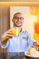 a man is holding a glass of orange juice at VIVE Hotel Waikiki in Honolulu