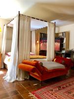 a bedroom with a canopy bed with an orange couch at La Maison d&#39;Alice in Vézac