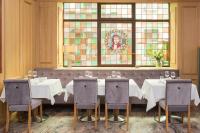 a dining room with a table and chairs and a stained glass window at Hôtel Le Rapp in Colmar