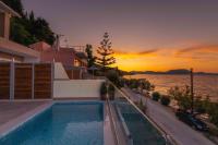 a swimming pool on the roof of a house with the sunset at Valtes Luxurious Apartments in Mpoukaris