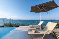 a pair of chairs and an umbrella next to a swimming pool at Valtes Luxurious Apartments in Mpoukaris