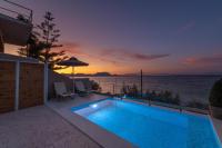 a swimming pool with a view of the ocean at sunset at Valtes Luxurious Apartments in Mpoukaris