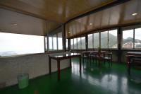 a room with tables and chairs in a building with windows at Shi-Jia B&amp;B in Jiufen