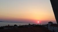 a sunset over the ocean with houses and roofs at Apartman Joso in Diklo