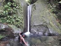 a boy in a pool of water in front of a waterfall at Fetay Jaune in Baie-Mahault