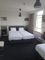 a hotel room with two beds and a chair at Stad &amp; Strandhotel Elisabeth in Vlissingen