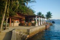 a restaurant next to the water with palm trees at Pousada e Mergulho Jamanta in Angra dos Reis